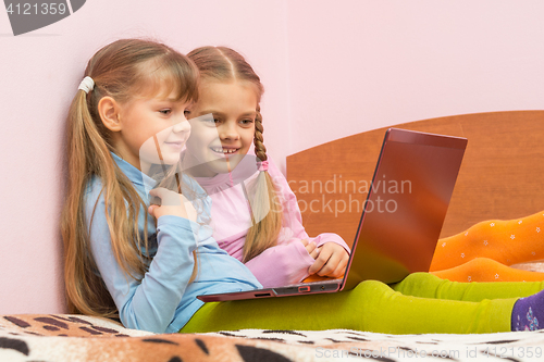 Image of Two girls watching something funny in notebook