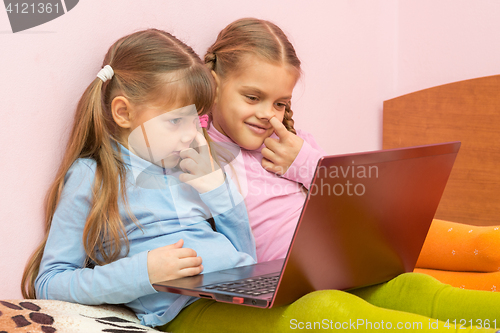 Image of Two girls picking his nose and looking at a laptop screen