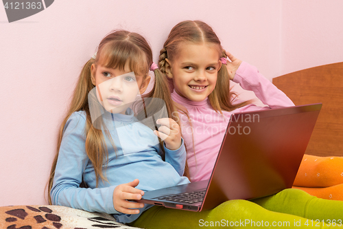 Image of Two girls were distracted from the laptop and looked toward