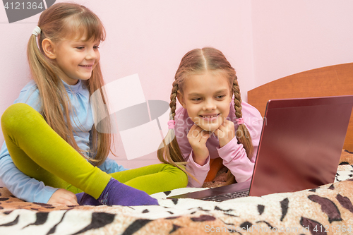 Image of Two girls looking at a laptop and laughing together having fun