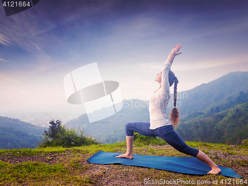 Image of Woman doing yoga asana Virabhadrasana 1 - Warrior pose outdoors