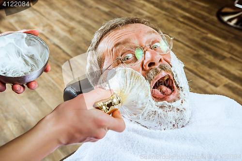 Image of The senior man visiting hairstylist in barber shop.