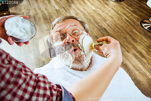 Image of The senior man visiting hairstylist in barber shop.