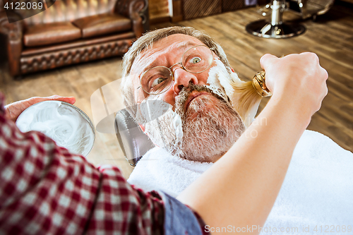 Image of The senior man visiting hairstylist in barber shop.