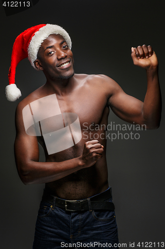 Image of Muscular black shirtless young man in Santa Claus hat