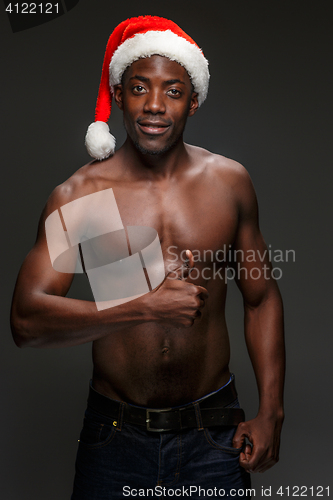 Image of Muscular black shirtless young man in Santa Claus hat