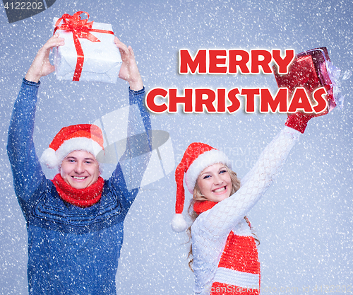 Image of The woman and man dressed in santa hat holding with a Christmas gifts