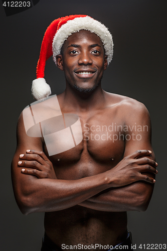 Image of Muscular black shirtless young man in Santa Claus hat