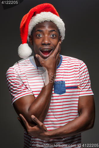 Image of Muscular black surprised young man in Santa Claus hat