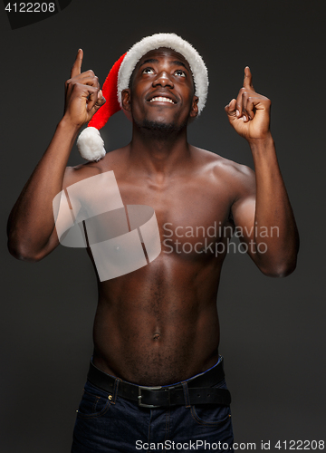 Image of Muscular black shirtless young man in Santa Claus hat