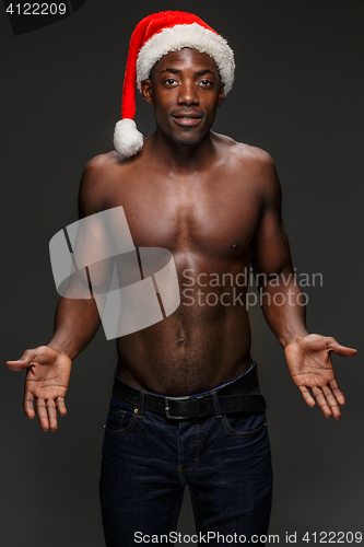 Image of Muscular black shirtless young man in Santa Claus hat