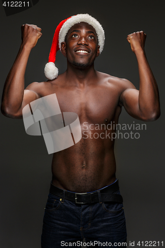 Image of Muscular black shirtless young man in Santa Claus hat