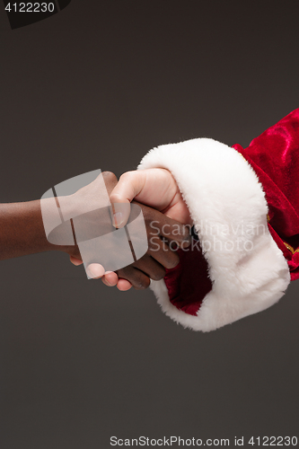 Image of The handshake of Santa Claus hand and hand of african man