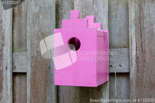 Image of Pink birdhouse on a wooden fence