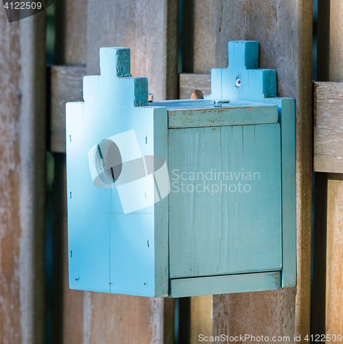 Image of Blue birdhouse on a wooden fence