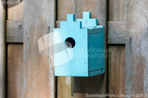 Image of Blue birdhouse on a wooden fence