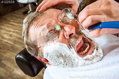 Image of The senior man visiting hairstylist in barber shop.