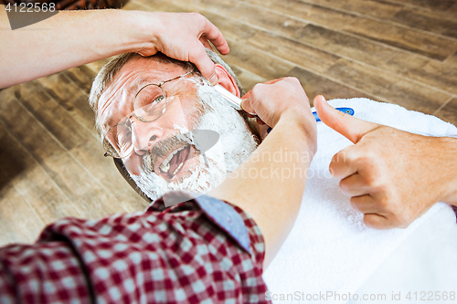 Image of The senior man visiting hairstylist in barber shop.