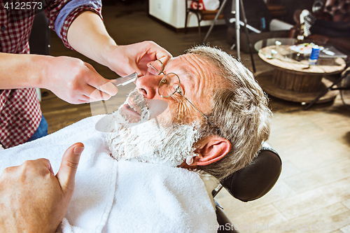 Image of The senior man visiting hairstylist in barber shop.