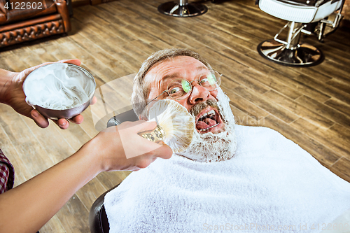 Image of The senior man visiting hairstylist in barber shop.