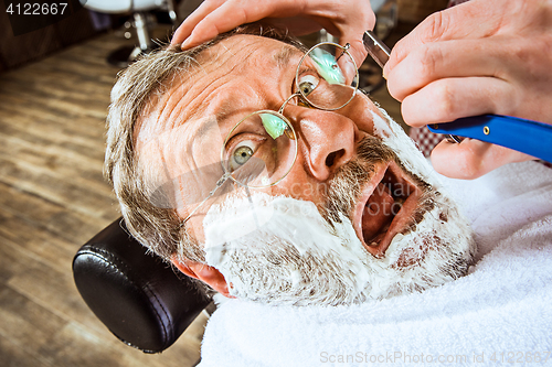 Image of The senior man visiting hairstylist in barber shop.