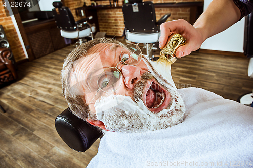 Image of The senior man visiting hairstylist in barber shop.