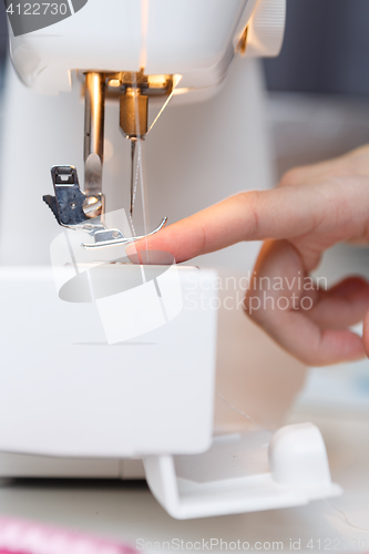 Image of Seamstress put thread in needle