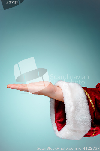 Image of Santa Claus hand presenting your text or product on blue background