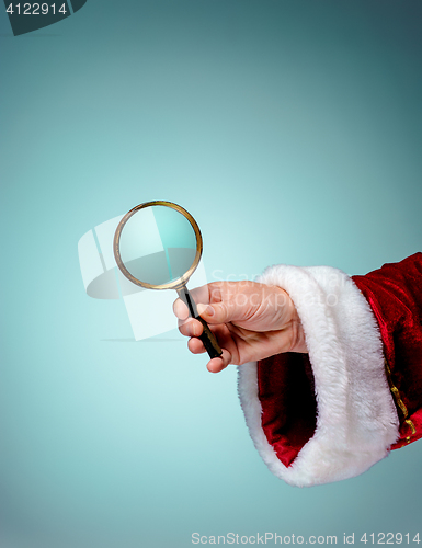 Image of Photo of Santa Claus hand with a magnifying glass