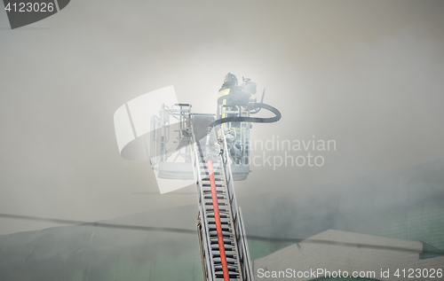 Image of Firefighters in action fighting, extinguishing fire, in smoke.