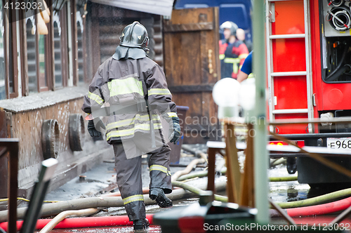 Image of fire fighters walking away building in the drops of water after putting out the