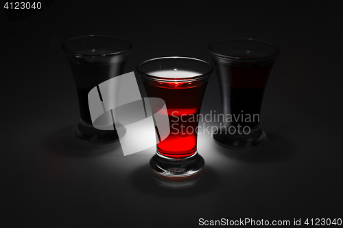 Image of red and tow shot glass on a dark background in the spot light