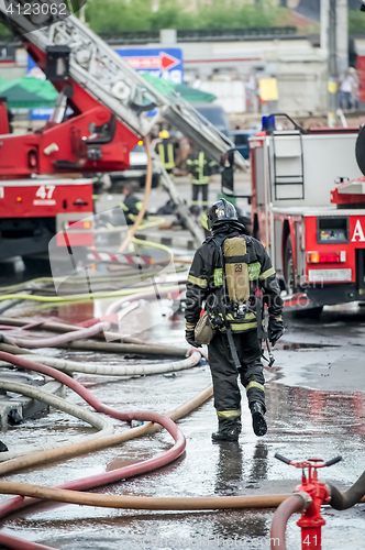 Image of fire fighters walking away building in the drops of water after putting out the