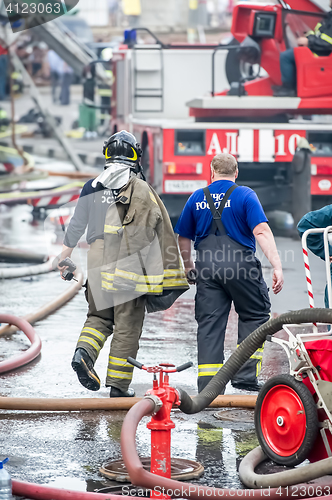 Image of fire fighter and rescuer walking away building in the drops of water after putting out the