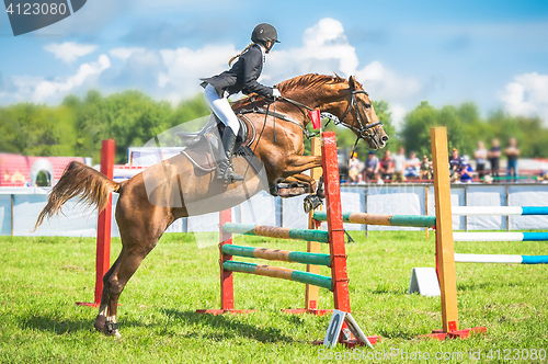 Image of young, female jockey on her horse leaping over a hurdle.