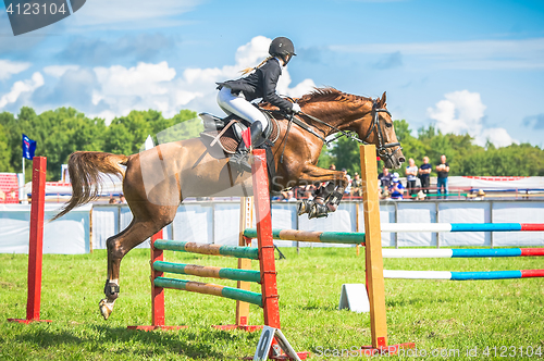 Image of young, female jockey on her horse leaping over a hurdle.