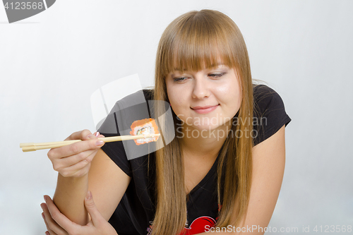 Image of Young girl eats rolls with wooden chopsticks