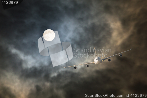 Image of Long-haul night flight through clouds in light of full moon