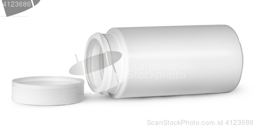 Image of White plastic bottle for vitamins lying near lid