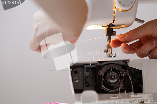 Image of Girl inserts thread in sewing-machine