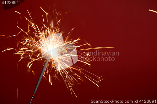 Image of Flaming sparkler on red background