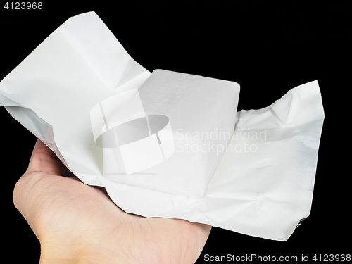 Image of Unwrapped block of coconut fat in aluminium paper held by a pers