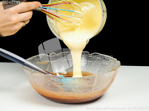 Image of Female person pouring Gogl-Mogl, into a glass bowl with chocolat