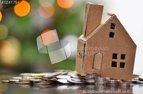 Image of Model of house with coins on wooden table 