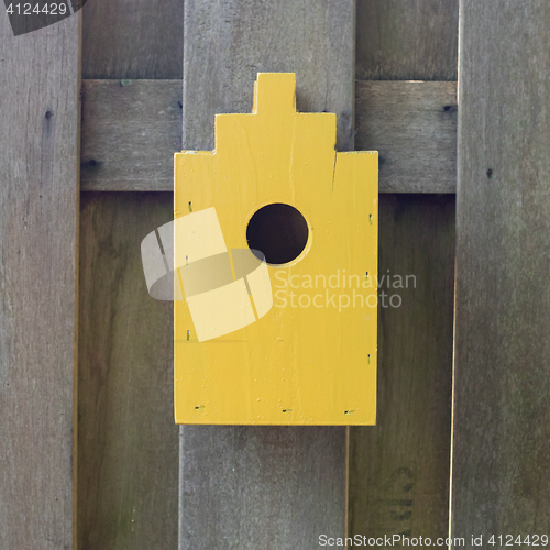 Image of Yellow birdhouse on a wooden fence