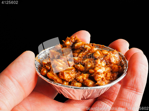 Image of Person holding puffed rice with chocolate cake in aluminum cup, 