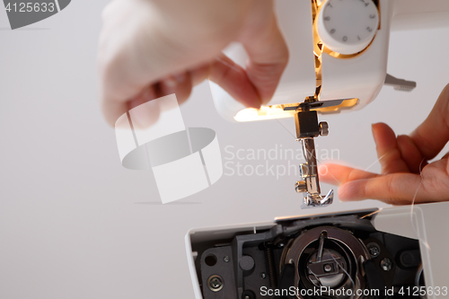 Image of Seamstress inserts thread in sewing-machine
