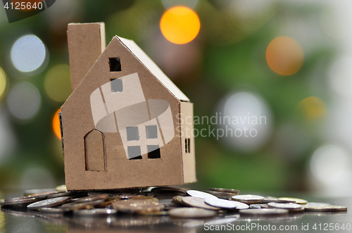 Image of Model of house with coins on wooden table