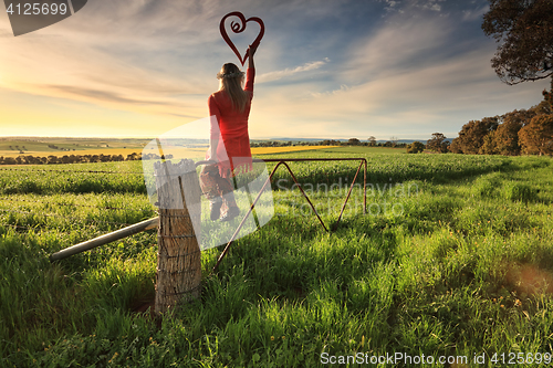 Image of Escape to the Country - female on fence with love heart in morni