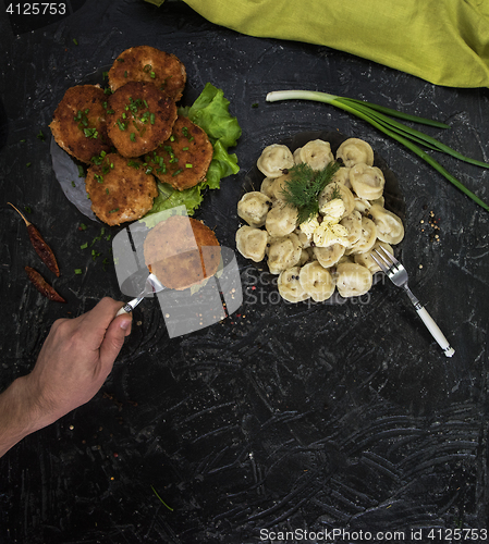 Image of Fried cutlets and russian pelmeni on black background